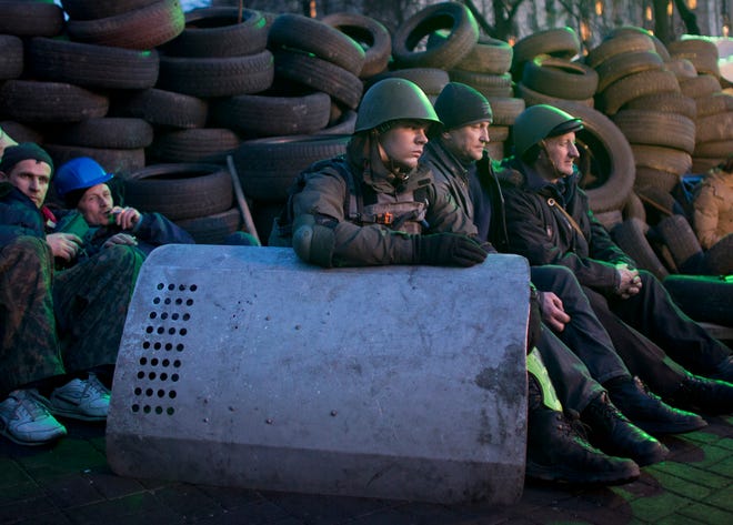 Anti-government protesters rest at a barricade in central Kiev, Ukraine, on Friday. UkraineÕs bloody political crisis moved swiftly toward a possible solution Friday as the opposition signed a deal with the embattled president, and parliament changed the constitution and opened the way for the release of ex-Prime Minister Yulia Tymoshenko.