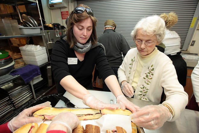 Life Engagement Director at Bridges Sarah Turcotte, left, helps Jean Coleran put the sandwiches in a metal tray while getting ready to help out with lunch on a recent Friday at Father Bill's in Quincy.