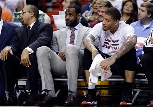 Miami Heat's LeBron James, center, watches from the bench with teammate Michael Beasley, right, during the first half of an NBA basketball gam against the Chicago Bulls, Sunday, Feb. 23, 2014, in Miami. James is not playing as he is recovering from a broken nose. (AP Photo/Lynne Sladky)