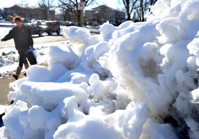 An Iowa State University student walks by a pile of snow and ice on Union Drive on a chilly afternoon Wednesday in Ames. Photo by Nirmalendu Majumdar/Ames Tribune