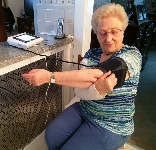 Helen Alpers, 82, demonstrates how she uses a health monitoring device provided by Greater Medford Visiting Nurse Association, which sends health data to nurses and doctors, who check the information daily and receive alerts when the self-administered tests produce irregular results. Wicked Local Photo/Alex Ruppenthal