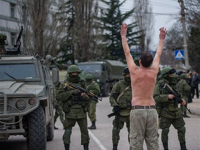 A Ukrainian man stands in protest in front of gunmen in unmarked uniforms as they stand guard in Balaklava, on the outskirts of Sevastopol, Ukraine, Saturday, March 1, 2014. An emblem on one of the vehicles and their number plates identify them as belonging to the Russian military. Ukrainian officials have accused Russia of sending new troops into Crimea, a strategic Russia-speaking region that hosts a major Russian navy base. The Kremlin hasnít responded to the accusations, but Russian lawmakers urged Putin to act to protect Russians in Crimea.