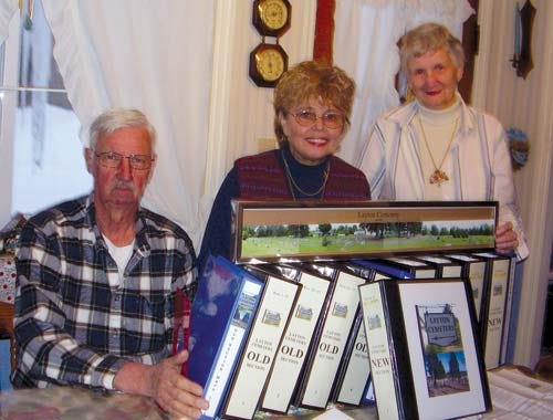 Thomas Horsfield, left, Sharon Spangenberg, center, and Nan S. Horsfield of the Layton (Centreville) Cemetery Association, show off a panoramic view of the cemetery and the 10 loose-leaf notebooks containing data and photographs of its history.