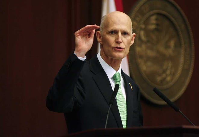 Florida Gov. Rick Scott talks about raising the bar on his jobs prediction numbers during his State of the State speech Tuesday, March 4, 2014, on the floor of the House of Representatives at the Capitol in Tallahassee, Fla. Scott touted Florida's improving economy in his speech that drew a contrast between the recession years under former Gov. Charlie Crist and the jobs created during his first three years in office. (AP Photo/Phil Sears)