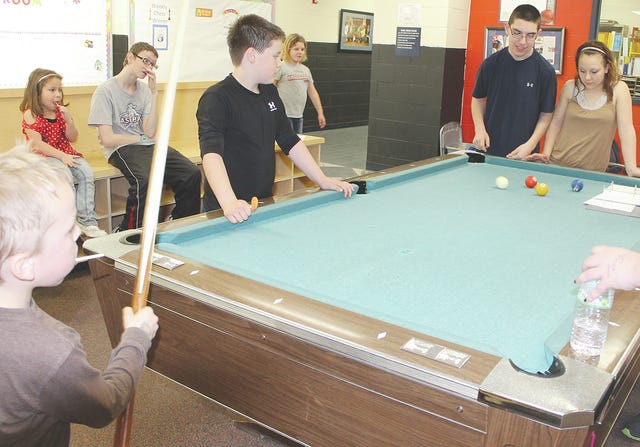 TANIAH TUDOR • PRESS ARGUS-COURIER Junior staff members Zach Grogg, 16, and Christy Rogers, 14, stand at the end of the pool table at the Boys and Girls Club of Alma while kids wait for a chance to play. 
  TANIAH TUDOR • PRESS ARGUS-COURIER Kolby Johnson, 16, sweeps the floor of the front lobby as part of his duties as a Junior Staff member.