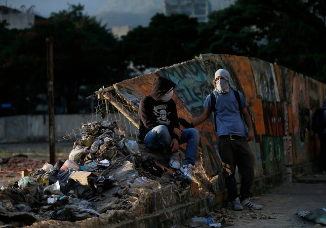 Anti-government demonstrators take a break during clashes with security forces in Caracas, Venezuela, Wednesday, March 5, 2014. The one year anniversary of the death of Venezuela's former President Hugo Chavez was marked with a mix of street protests and solemn commemorations that reflected deep divisions over the Venezuela he left behind.