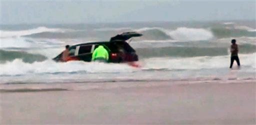 In this image made from video and released by Simon Besner, lifeguards rescue children from a minivan that their mother drove into the Atlantic Ocean, Tuesday, March 4, 2014 in Daytona Beach, Fla. Ebony Wilkerson, 31, a pregnant South Carolina woman who drove a minivan carrying her three young children into the ocean surf off Florida had talked about demons before leaving the house, according to her sister who worriedly called police, officials said during a news conference Wednesday. Bystanders and officers helped pull Wilkerson and her children, ages 3, 9 and 10, from their minivan. The children were turned over to welfare authorities. The Volusia County Sheriff's Office says Wilkerson was undergoing a mental evaluation. (AP Photo/Simon Besner)