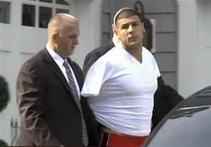 In this image taken from video, police escort Aaron Hernandez from his home in handcuffs in Attleboro on June 26, 2013. Hernandez was taken from his home more than a week after a Boston semi-pro football player was found dead in an industrial park a mile from Hernandez's house.