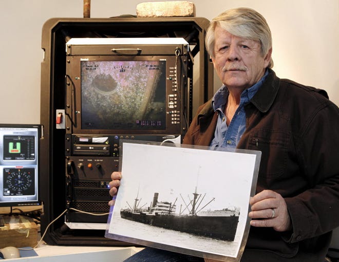 Greg Brooks, co-manager of Sub Sea Research, is seen aboard the salvage ship Sea Hunter in Boston Harbor Wednesday, Feb. 1, 2012 holding a picture of the British merchant ship Port Nicholson which was sunk by a German U-boat in 1942.