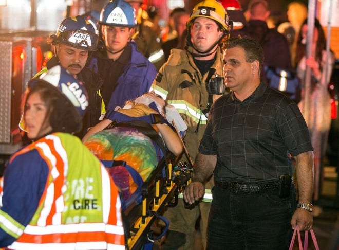 A parent accompanies his injured daughter as firefighters carry her from Servite High School after a stage collapsed during a student event at the high school in Anaheim, Calif., Saturday, March 8, 2014. Authorities said 30-40 people were rushed to hospitals with mainly minor injuries. (AP Photo/Kevin Warn)