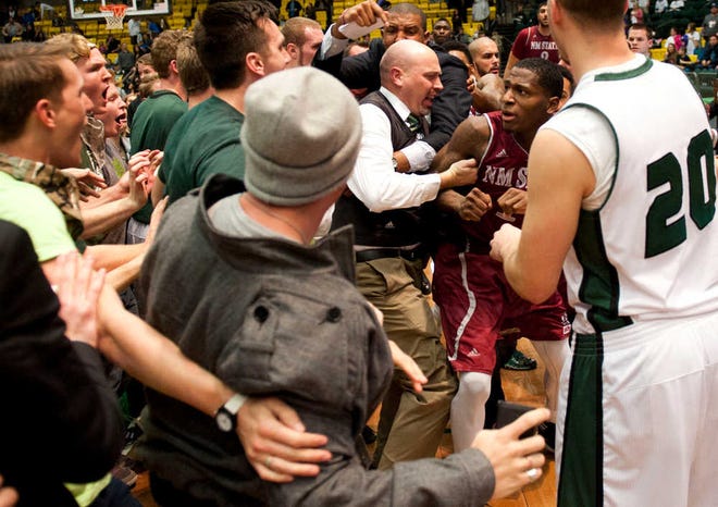 In this Thursday, Feb. 27, 2014 photo, New Mexico State's DK Eldridge, at right center in red and white uniform, is controlled by security during a brawl involving players and fans who came onto the court when New Mexico State guard K.C. Ross-Miller hurled the ball at Utah Valley's Holton Hunsaker seconds after the Wolverines' 66-61 overtime victory against the Aggies in Orem, Utah. (AP Photo/The Daily Herald, Grant Hindsley) MANDATORY CREDIT