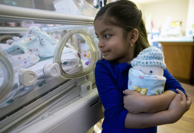 Angelica Garcia, 5, holds the doll she helped make as she visits her brother in the neonatal intensive care unit at Baylor All Saints Medical Center in Fort Worth, Texas. The doll, filled with rice, weighs the same amount as her brother did when he was born, less than 2 pounds. It is a reminder that both brother and doll are fragile and must be cherished.