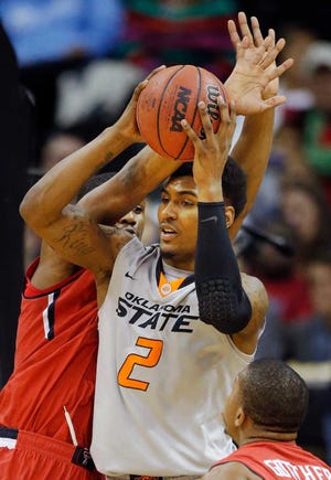 Oklahoma State forward Le'Bryan Nash, right, passes to a teammate Wednesday while covered by Texas Tech forward Jordan Tolbert during the first half of a game in the Big 12 men's tournament in Kansas City, Mo.
