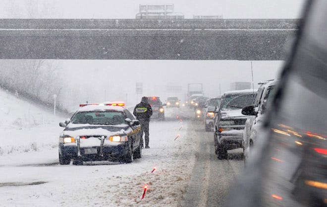 A New York State trooper places flares along the Thruway entrance ramp from I-81 northbound where a tractor trailer was disabled in Syracuse, N.Y.