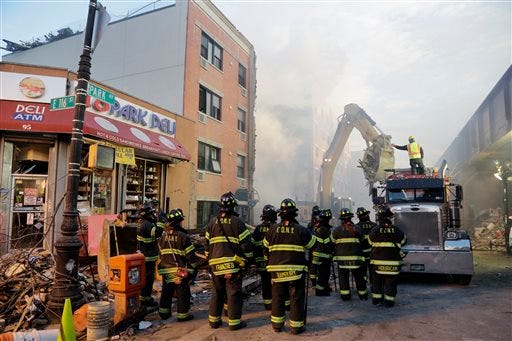 An excavator removes debris from the site of a building explosion, Thursday, March 13, 2014 in New York. Rescuers working amid gusty winds, cold temperatures and billowing smoke pulled four additional bodies Thursday from the rubble of two New York City apartment buildings, raising the death toll to at least seven from a gas leak-triggered explosion that reduced the area to a pile of smashed bricks, splinters and mangled metal. The explosion Wednesday morning in Manhattan's East Harlem injured more than 60 people.