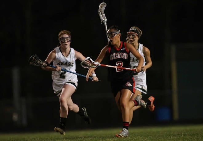 Creekside's Paige Farrar (2) is defended by Nease's Mary Gormley (2) and Adriana Quintana (22) during a lacrosse game at Nease High School on Thursday, March 13, 2014. By Perry Knotts, Special to The Record.