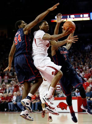 Marc F. Henning * Arkansas News Bureau  Arkansas' Coty Clarke takes the ball to the basket between Ole Miss' Aaron Jones, left, and Martavious Newby during the Razorbacks' game Wednesday, March 5, 2014, against the Rebels at Bud Walton Arena in Fayetteville, Ark.