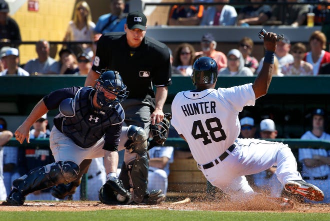 Detroit Tigers' Torii Hunter (48) begins his slide as New York Yankees catcher Brian McCann, left, waits to make the tag at home in front of umpire Andy Fletcher during the third inning of an exhibition spring training baseball game in Lakeland, Fla., Friday, Feb. 28, 2014. Hunter was attempting to score on a single to left field by Tigers' Miguel Cabrera. The Yankees won 7-4. (AP Photo/Gene J. Puskar)