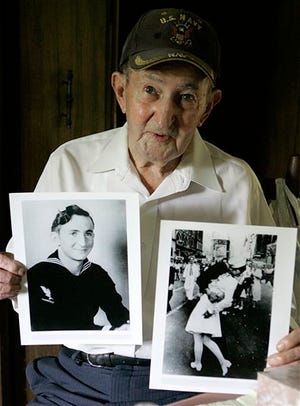 FILE - In this July 31, 2007 file photo, Glenn McDuffie holds a portrait of himself as a young man, left, and a copy of Alfred Eisenstaedt's iconic Life magazine shot of a sailor, who McDuffie claims is him, embracing a nurse in a white uniform in New York's Times Square, at his Houston home. McDuffie, who became known for claiming he was the sailor kissing a woman in Times Square in a famous World War II-era photo taken by a Life magazine photographer has died. Houston Police Department forensic artist Lois Gibson, who says she identified McDuffie as the man in the picture, says Friday, March 14, 2014 that he died March 9. McDuffie was 86. (AP Photo/Pat Sullivan, File)