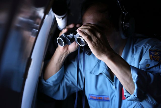 THE ASSOCIATED PRESS/ Vietnamese Air Force Col. Pham Minh Tuan uses binoculars on board a flying aircraft during a mission to search for the missing Malaysia Airlines flight MH370 in the Gulf of Thailand on Thursday. With no distress call, no sign of wreckage and very few answers, the disappearance of the Malaysia Airlines plane is turning into one of the biggest aviation mysteries since Amelia Earhart vanished over the Pacific Ocean in 1937.