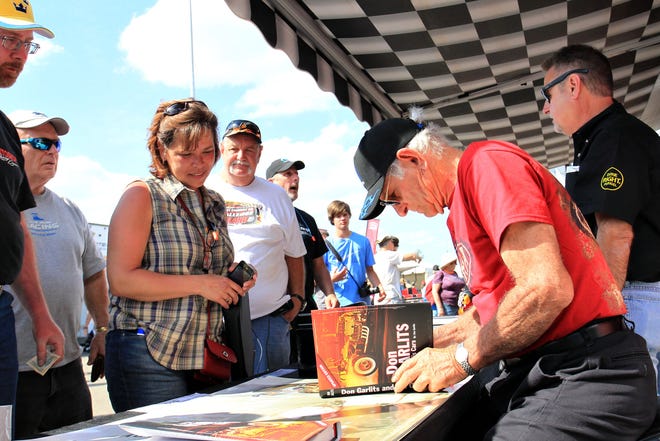 Don "Big Daddy" Garlits signs a copy of his book for a race fan in the pit area at the Amalie Motor Oil Gatornationals at the Auto Plus Raceway in Gainesville Saturday March 15, 2014.
