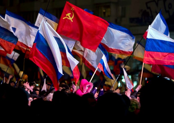 Pro-Russian people celebrate in Lenin Square, in Simferopol, Ukraine, Sunday, March 16, 2014. Fireworks exploded and Russian flags fluttered above jubilant crowds Sunday after residents in Crimea voted overwhelmingly to secede from Ukraine and join Russia. The United States and Europe condemned the ballot as illegal and destabilizing and were expected to slap sanctions against Russia for it. (AP Photo/Vadim Ghirda)
