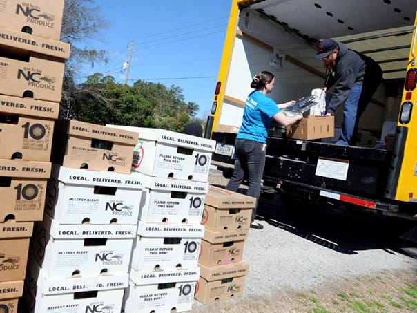 Lisa Roddey, left, a neighborhood coordinator with The Produce Box, and route manager Aharon Segal unload produce boxes prior to delivery at Roddey's house in Wilmington, North Carolina Thursday, March 13, 2014.