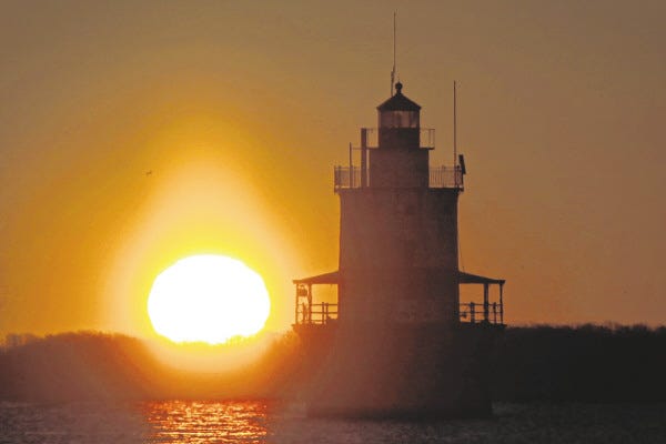 The sun rises behind the iconic Butler Flats lighthouse Friday morning.