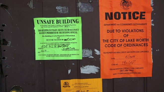 Signs visible on the front door of an abandoned house on South L Street in Lake Worth Monday, March 10, 2014 include an unsafe building warning, a code violation citation notice, and a Board and Secure Notice. (Bruce R. Bennett / The Palm Beach Post)