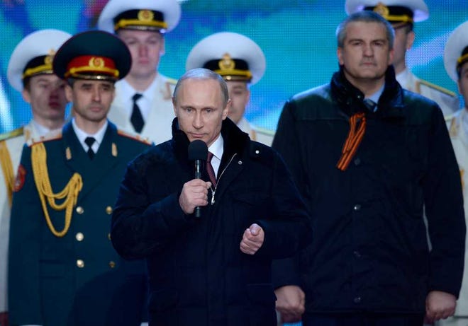 Russian President Vladimir Putin speaks at a rally in support of Crimea joining Russia, in Red Square in Moscow, Tuesday, March 18, 2014. With a sweep of his pen, President Vladimir Putin added Crimea to the map of Russia on Tuesday, describing the move as correcting past injustice and responding to what he called Western encroachment upon Russia's vital interests. At right is Crimean Premier Sergei Aksyonov. (AP Photo/RIA-Novosti, Alexei Nikolsky, Presidential Press Service)
