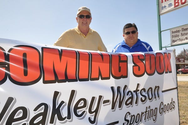 David Furry (left), owner of Weakley-Watson Sporting Goods, and Gerry Laing, manager of the sports goods store, stand behind a sign proclaiming that the store's new home will be in the 500 block of Early Boulevard in Early.