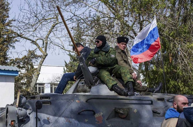 Crimean self-defense force members sit atop an APC with a Russian flag outside the Ukrainian navy headquarters stormed by Crimean self-defense forces in Sevastopol, Crimea, Wednesday, March 19, 2014. Crimea's self-defense forces on Wednesday stormed the Ukrainian navy headquarters in the Black Sea port of Sevastopol, taking possession without resistance a day after Russia signed a treaty with local authorities to annex the region. (AP Photo/Andrew Lubimov)
