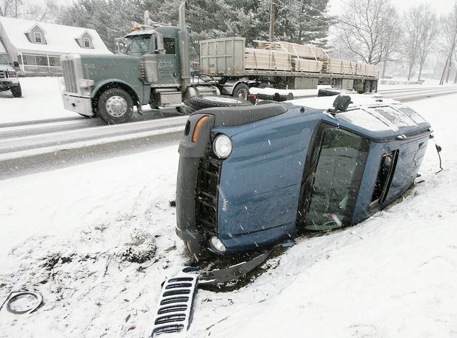 A semi drives by slowly, checking the Jeep Liberty that slid off the road and rolled on its side about one mile south of Sarbaugh Street on route 93 in Tuscarawas Township. No one was reported to be injured.