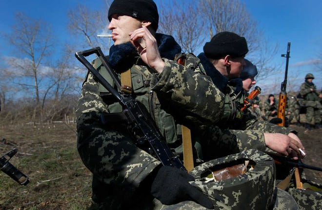 Ukrainian border guards take a break during training at a military camp in the village of Alekseyevka on the Ukrainian-Russian border, eastern Ukraine, Friday, March 21, 2014. Russian President Vladimir Putin signed bills on Friday making Crimea part of Russia, completing the annexation from Ukraine. (AP Photo/Sergei Grits)