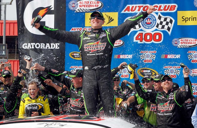 Kyle Busch, center, celebrates, as the team drenches his wife, Samantha Busch, left, in victory circle after winning the NASCAR Sprint Series auto race in Fontana, Calif., Sunday, March 23, 2014. (AP Photo/Alex Gallardo)