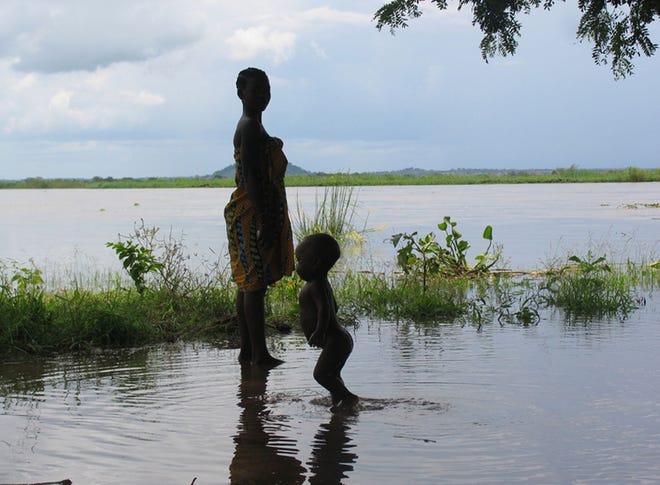 In this Jan. 9, 2008, file photo provided by UNICEF a woman and child wade in flood waters in Mutarara, Mozambique in the Tete district. Thousands of people who lost their homes in floods last year are at risk again as the rising Zambezi river waters threaten their resettlement camps. Top climate scientists are gathering in