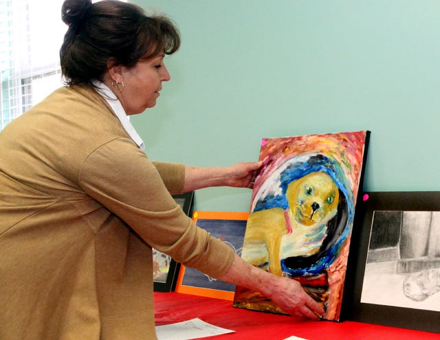 Jamie Mitchell • Times Record - Sebastian County Humane Society executive director Jo Ann Barton arranges artwork Saturday, March 22, 2014, for the SCHS clinic art show and silent auction. Southside High School art students created 20 pieces of artwork, including paintings and sketches, for the silent auction. Proceeds go to the humane society operating fund.