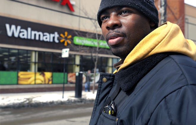 In this Tuesday, March 4, 2014, photo, Wal-Mart employee Richard Wilson, 27, is photographed outside the store where he works in Chicago. Wilson earns $9.25 an hour at that Wal-Mart and lives on the city’s western edge with his grandmother.