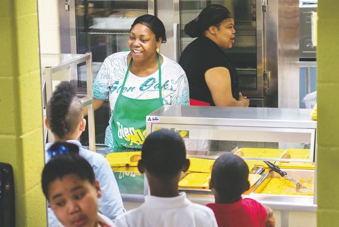 Shonn Pierce, back left, serves up corn, pears, salad and other items to students during school lunch at Glen Oak Community Learning Center on Thursday in Peoria. Federal and state officials want to see the Summer Food Service Program become as common and the National School Lunch Program.