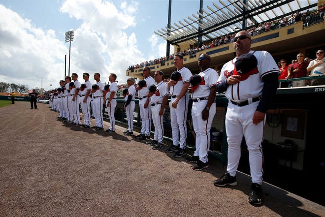Atlanta Braves manager Fredi Gonzalez, right, stands with his team for the National Anthem before a spring exhibition baseball game against the Washington Nationals, Tuesday, March 4, 2014, in Kissimmee, Fla. (AP Photo/Alex Brandon)