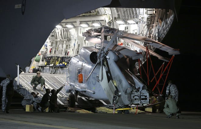 Ground crew unload a Sea Hawk helicopter from a Royal Australia Air Force C-17 after it landed at RAAF Base Pearce to help with the search for the missing Malaysia Airlines Flight MH370 in Perth, Australia, Friday, March 28, 2014. Australian officials moved the search area for the lost Malaysian jetliner 1,100 kilometers (680 miles) to the northeast Friday, following a new analysis of radar data, and a plane quickly found objects that a ship set out to investigate.