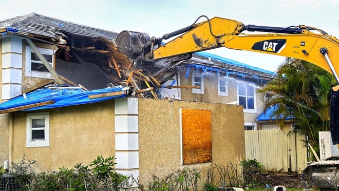 An excavator tears into a house at 13932 Folkstone Circle in Wellington Friday morning, March 28, 2014. The blighted home has plagued the neighborhood for several years.