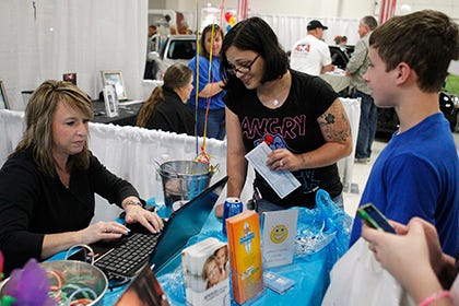 Coastal Carolina Orthodontics office manager Pam Smith makes an appointment on site with Amanda Winter, seen with her 13-year-old son Gabriel, at the annual business expo presented by the Swansboro Area Chamber of Commerce at the Rotary Civic Center Saturday afternoon.