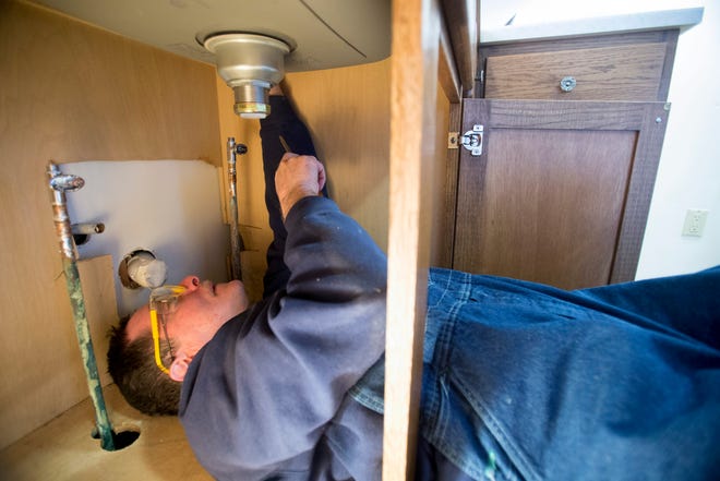 Pat Suddarth works under a kitchen sink Thursday, March 27, 2014, at an apartment building in the 2000 block of Douglas Street in Rockford.