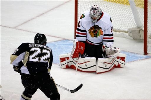 Pittsburgh Penguins' Lee Stempniak (22) puts the puck behind Chicago Blackhawks goalie Corey Crawford (50) for a goal in the first period of an NHL hockey game in Pittsburgh, Sunday, March 30, 2014.