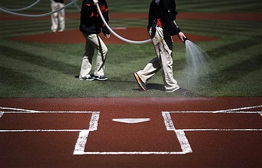 Groundskeepers water the infield before an opening day baseball game between the Baltimore Orioles and the Boston Red Sox, Monday, March 31, 2014, in Baltimore. (AP Photo/Patrick Semansky)