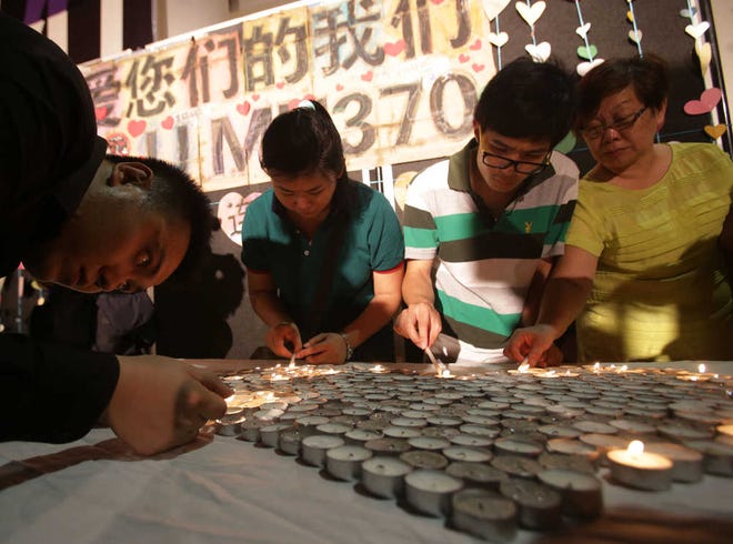 People light candles during a ceremony for the passengers on board the missing Malaysia Airlines flight MH370 in Kuala Lumpur, Malaysia, Sunday March 30, 2014. A new batch of relatives from China has arrived today to seek answers of what happened to their loved ones on board flight MH370. (AP Photo/Aaron Favila)