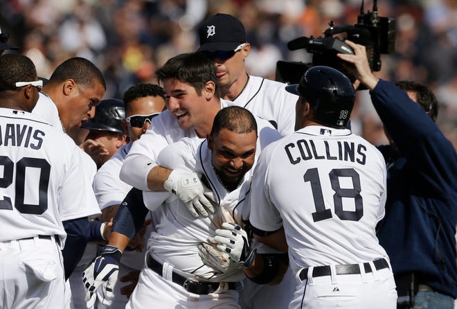 Detroit Tigers' Alex Gonzalez, center, is mobbed after hitting the game winning single to score the winning run from third during the ninth inning of a baseball game against the Kansas City Royals in Detroit, Monday, March 31, 2014. (AP Photo/Carlos Osorio)