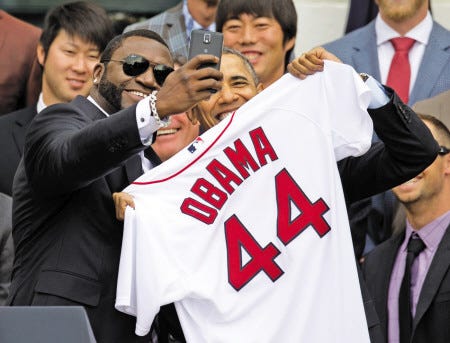 Boston Red Sox player David "Big Papi" Ortiz takes a selfie with President Barack Obama, holding a Boston Red Sox jersey presented to the president during a ceremony on the South Lawn of the White House in Washington, Tuesday, April 1, 2014, where the president honored the 2013 World Series baseball champion Boston Red Sox. In the background are pitchers Junichi Tazawa, left, Koji Uehara, right. (AP Photo/Carolyn Kaster)