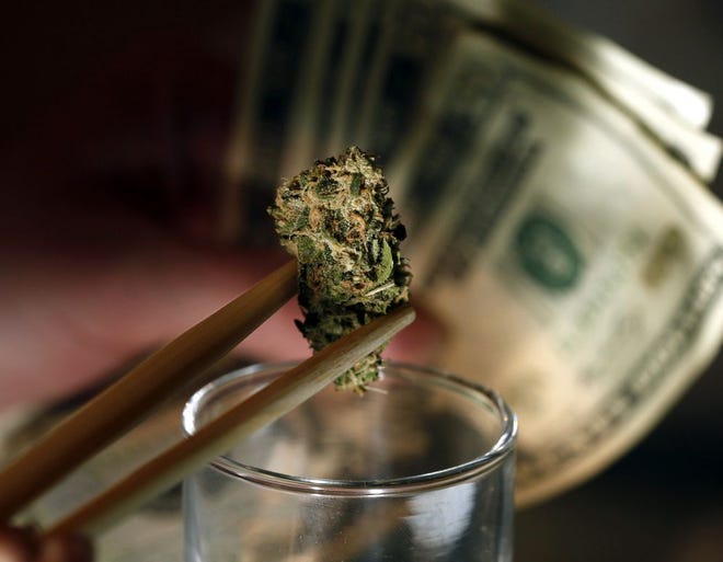 A caregiver picks out a marijuana bud for a patient at a marijuana dispensary in Denver.